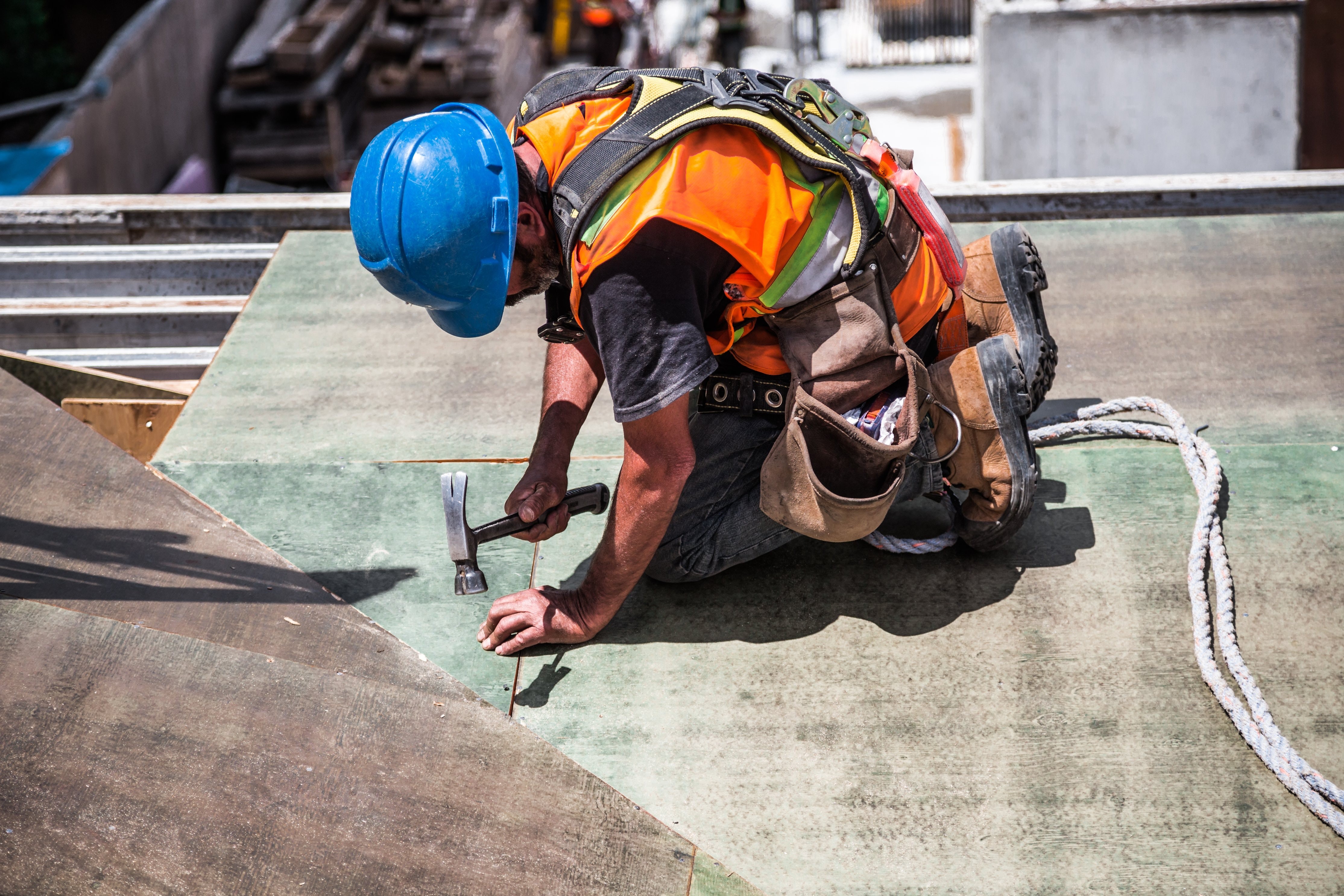 man wearing blue hard hat hammering