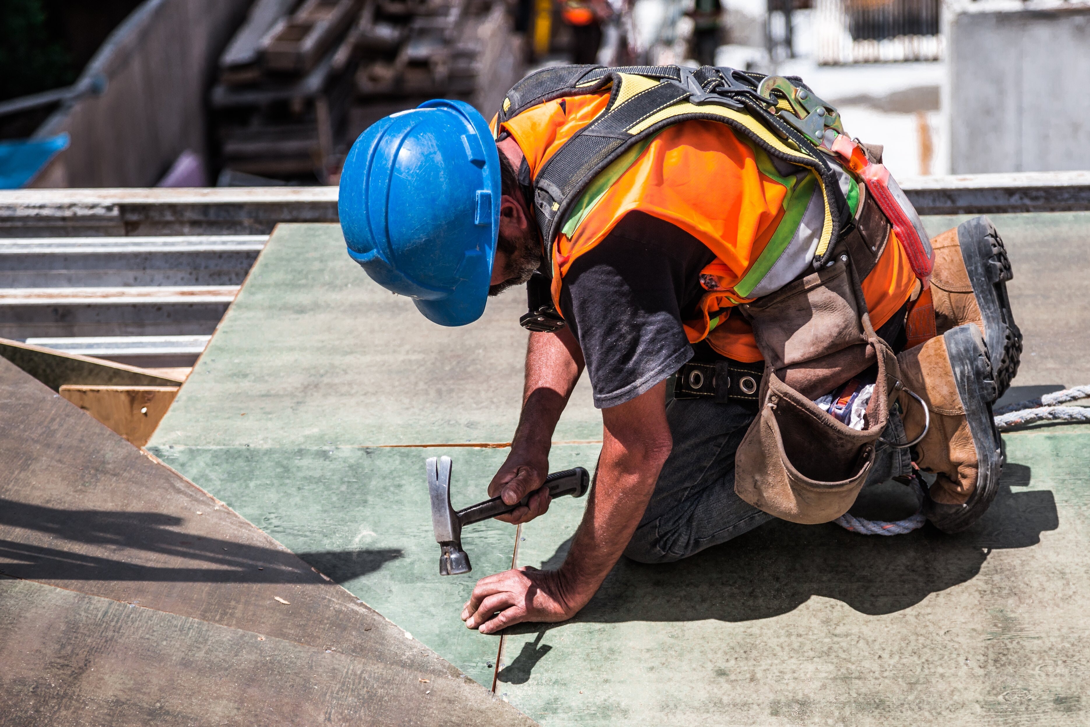 man wearing blue hard hat hammering