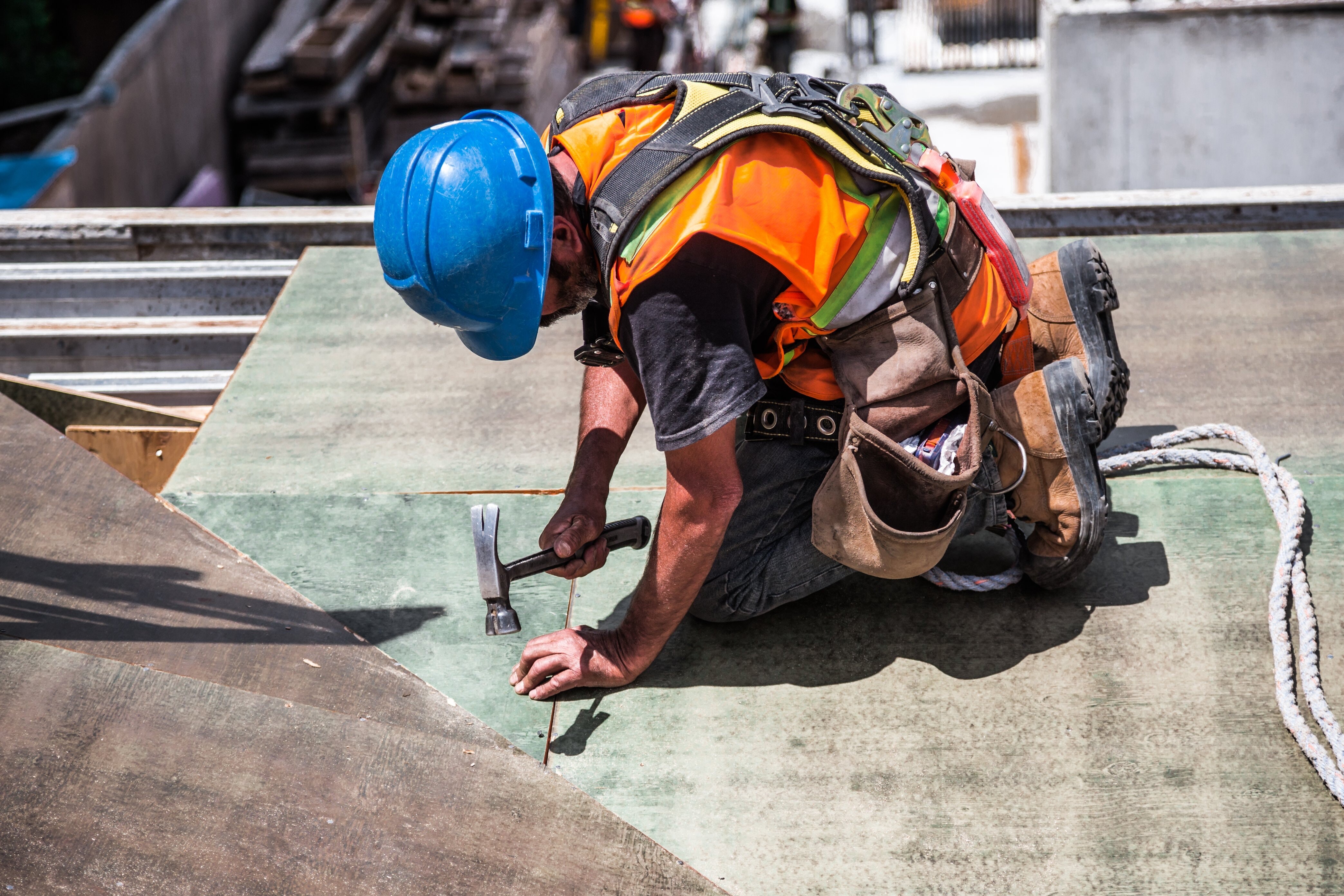 man wearing blue hard hat hammering