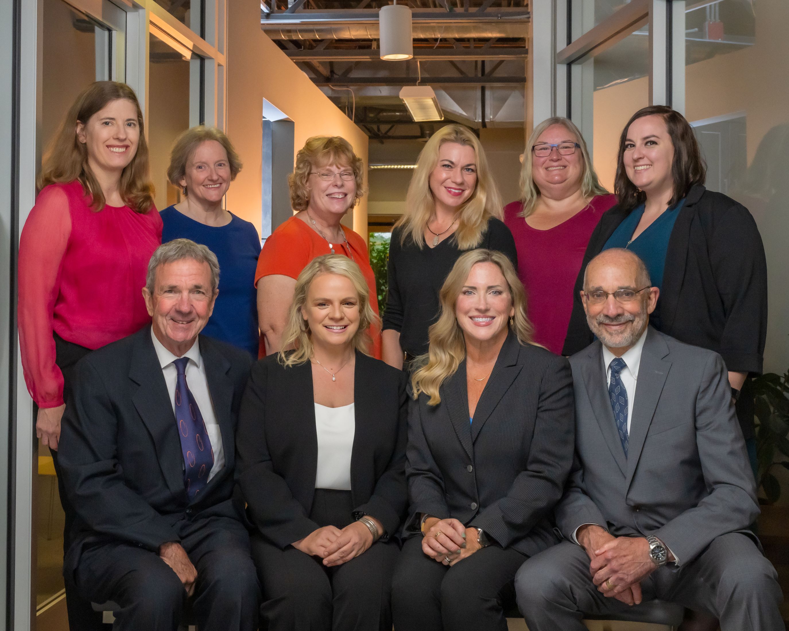 team photo with 4 attorneys seated in front of six support staff, all smiling at the camera