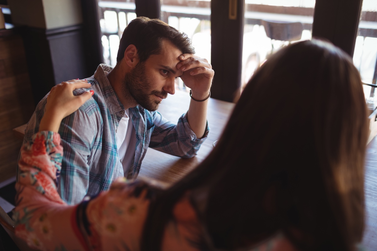 A woman consoling a man at a table