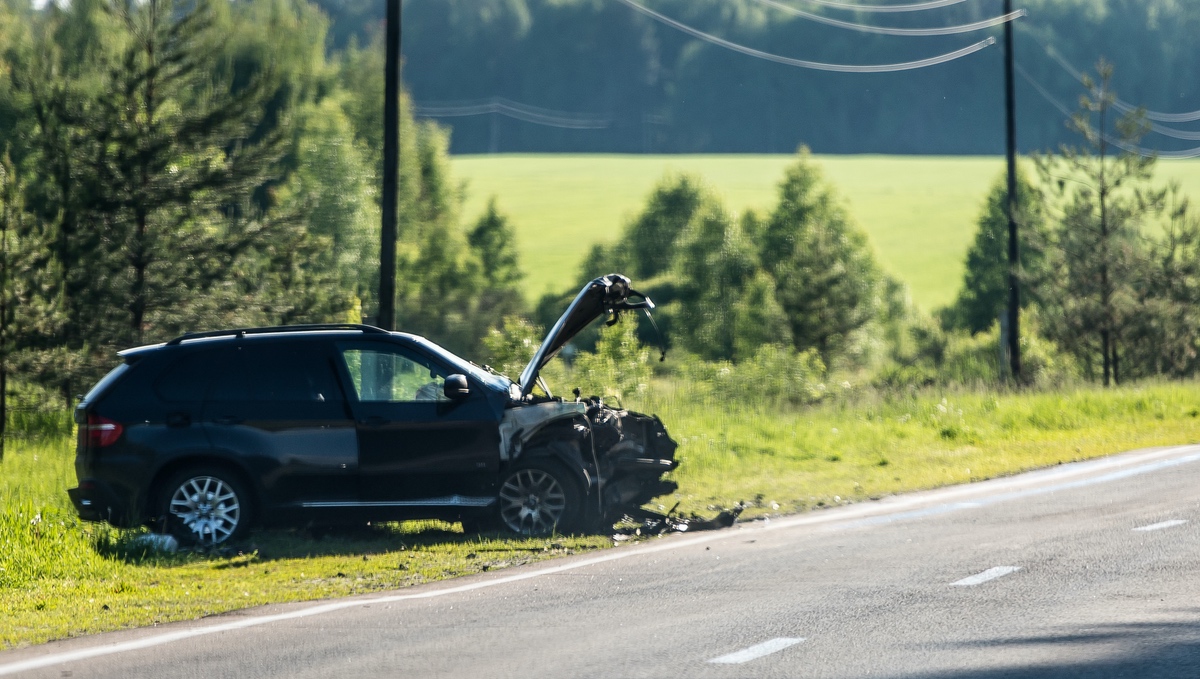 A car off the side of the road with a crushed front end