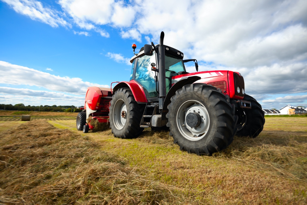 A big red tractor in a field on a farm