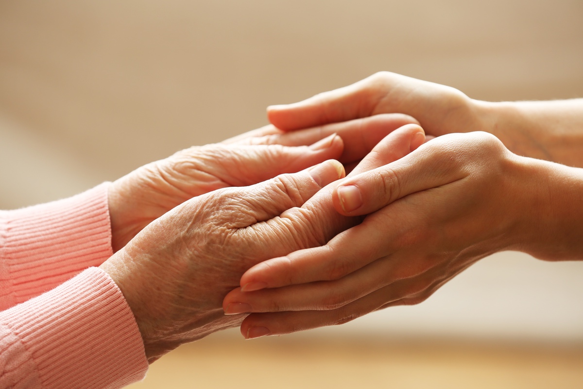 Two women holding hands in a gesture of caring